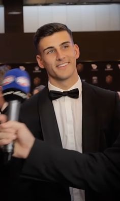 a man in a tuxedo holding a microphone