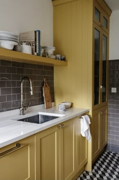 a kitchen with yellow cabinets and black and white checkered flooring on the walls