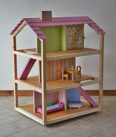 the doll house is made out of wood and has pink trimmings on the roof