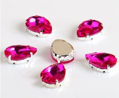 six pieces of bright pink jeweled jewelry on a white surface with one piece missing