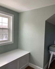 an empty room with a window and white bench