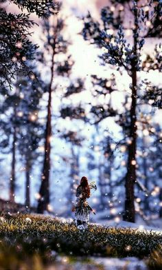 a woman is walking through the woods with snow falling on her and trees in the background