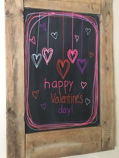 a chalkboard with hearts hanging from it's sides and the words happy valentine's day written on it