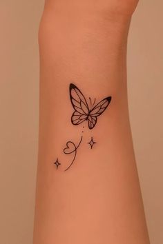 a small butterfly tattoo on the wrist with hearts and stars around it's wings