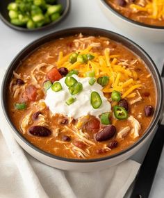 two bowls of chili cheese soup with sour cream on top