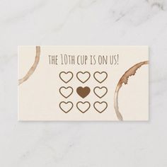 the 10th cup is on us with hearts and leaves in brown ink, sitting on a marble surface