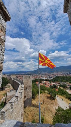 a red and yellow flag on top of a stone wall