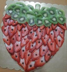 a heart shaped cake decorated with sliced strawberries and kiwis