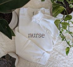 Nurse Floral Sweatshirt This Nurse sweatshirt features a beautiful floral design that adds a touch of femininity to this cozy sweatshirt. It is the perfect gift for the nurse in your life. Comes with a personalized sleeve featuring the nurse's name! Select options from dropdowns for sweatshirt color & size. 1. Name exactly as you want to appear. 2. Thread color for sleeve. (Refer to photos.) Welcome to The Threaded Daisy store. Thank you for visiting!  Production & Shipping: Everything is embroidered to order just for you. On average your items will be shipped out within 3-5 days of ordering. The estimated shipping time in the US is 5-7 business days. Washing Instructions: Wash inside out, in cold water, on gentle cycle.  Tumble dry on low or let air dry. Feedback: If you have any issues w Cotton Sweater With Floral Embroidery, White Floral Embroidered Sweatshirt For Fall, White Custom Embroidered Tops For Loungewear, Embroidered Long Sleeve Sweatshirt For Loungewear, Casual White Sweatshirt With Floral Embroidery, Embroidered Cotton Sweatshirt For Loungewear, Fall Cotton Sweatshirt With Floral Embroidery, White Floral Embroidery Sweatshirt With Relaxed Fit, White Floral Embroidered Sweatshirt Relaxed Fit