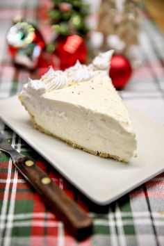 a piece of pie sitting on top of a white plate next to a knife and christmas decorations