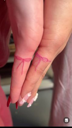 a woman's hand with pink nail polish and red bowknots on it