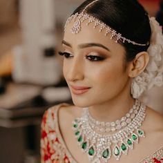 a woman in a red and white bridal outfit with jewels on her head, looking to the side