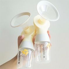 two baby bottles being held by someone's hand