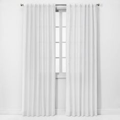 a white curtain hanging on the side of a window in front of a white wall