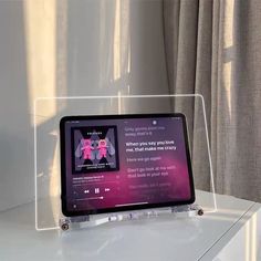 a tablet sitting on top of a white table next to a window with curtains behind it