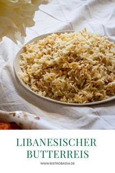 a white plate topped with lots of rice next to a yellow flower on top of a table