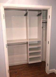 an empty walk in closet with white shelving and wood flooring on the side