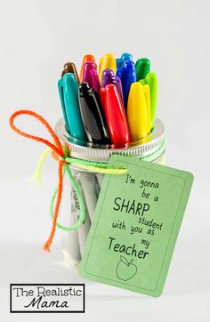 a jar filled with colorful markers next to a teacher's tag