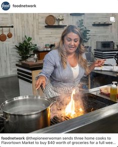 a woman cooking food on top of a grill next to a pot filled with flames