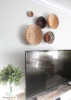 a flat screen tv sitting on top of a wooden shelf next to a potted plant