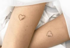 two people with tattoos on their legs, one has a heart and the other has a word