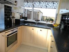 a kitchen with black counter tops and white cupboards next to a stove top oven