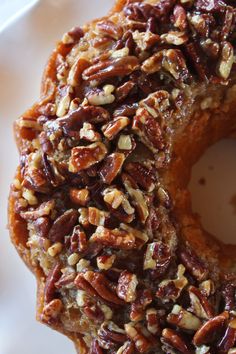 a close up of a doughnut on a plate with pecans and nuts around it