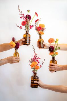 five arms holding warm-colored flowers in brown glass bud vases in front of a white background Background Color Palette, Color Palette Autumn, Palette Autumn, Daisy James, Dark Red Maroon, Dahlias Wedding, Brown Glass Bottles, Rose Dark, Gerber Daisy