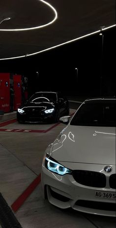 two cars parked in a parking garage with lights on the front and side of them