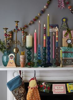 a mantle filled with lots of different types of candles and christmas decorations on top of it