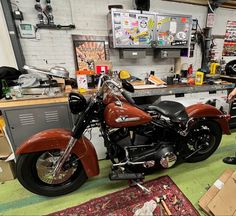 a man standing next to a red motorcycle in a room filled with boxes and other items