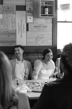 a man and woman sitting at a table with wine glasses