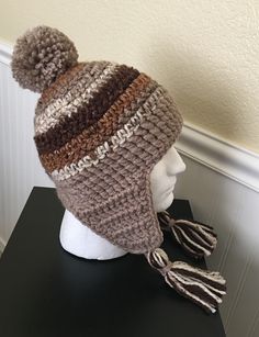 a crocheted hat with tassels on top of a mannequin head