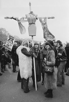 a group of people standing next to each other in front of a pole with clothes on it