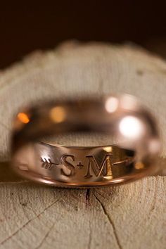 a close up of a wedding ring on top of a piece of wood with the letter s and m