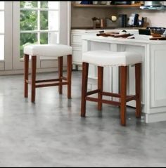 two white stools sitting in front of a kitchen counter