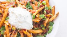 a white plate topped with french fries covered in ranch dressing