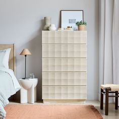 a bedroom scene with focus on the bed and white dresser unit in the foreground