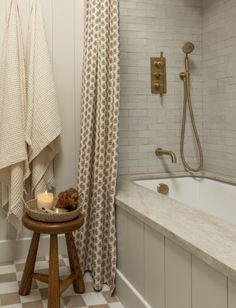 a bathroom with a checkered floor and white tiles on the walls, along with a wooden stool