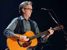 a man playing an acoustic guitar in front of a microphone