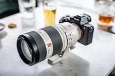 a camera sitting on top of a table next to a glass filled with liquid and other items