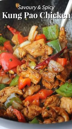 a wok filled with chicken, peppers and onions