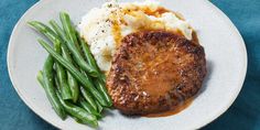 a white plate topped with meat, mashed potatoes and green beans