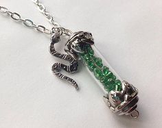 a silver necklace with green beads and a snake