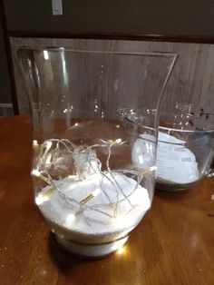 two clear vases sitting on top of a wooden table covered in white paper and string