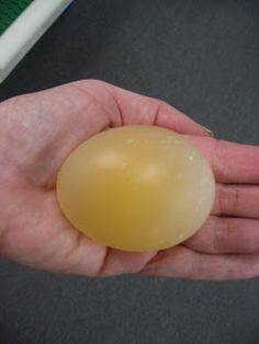 a person holding an egg in their hand on a table with a keyboard behind them