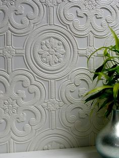 a potted plant sitting on top of a white table next to a wallpaper