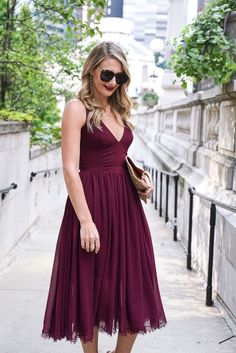 a woman in a purple dress is standing on the sidewalk