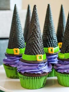 some cupcakes with witches hats on them are sitting on a white cake plate