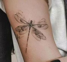 a woman's arm with a dragonfly tattoo on the left side of her arm